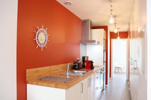 - une cuisine avec un mur orange et un évier dans l'établissement St Jean de Luz, Centre ville 2 pièces, plage à pied - 3 étoiles, à Sainte-Barbe