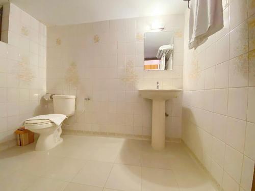 a white bathroom with a toilet and a sink at Crown Palace Residence in Dhaka