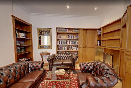 een woonkamer met lederen meubels en boekenplanken bij Hotel "Friedrich-Franz-Palais" in Bad Doberan