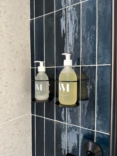 three bottles on a tiled wall in a bathroom at La place d'Henri, Rouen centre in Rouen