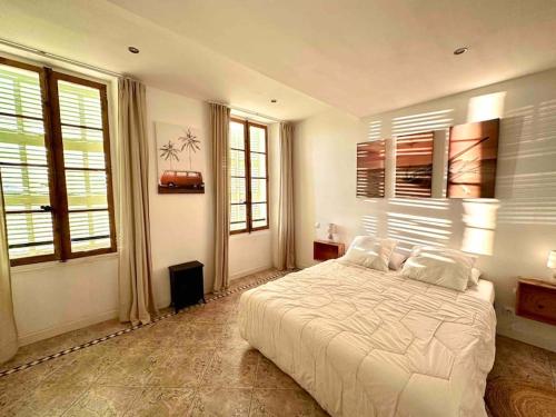 a bedroom with a large white bed and windows at Appart cosy au calme, dans le centre de Bandol in Bandol