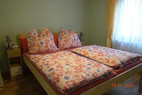 a bed with a comforter and pillows on it at Ferienwohnung Neue Schmiede 