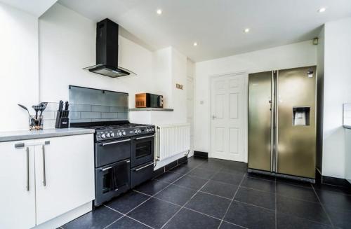 a kitchen with a stove and a stainless steel refrigerator at 3 Bed House, Perfect for Business and Contractors in Nottinghamshire in Plumtree
