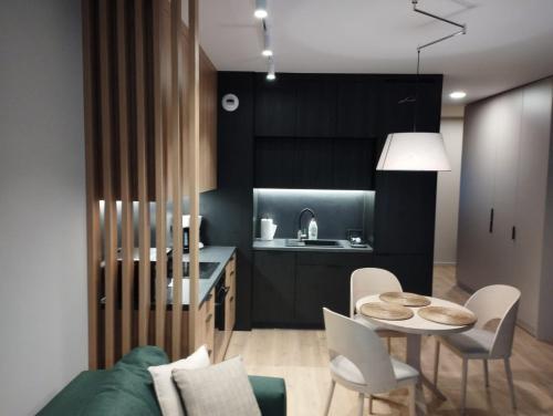 a kitchen with black cabinets and a table and chairs at Fantastyczny apartament Lotnisko in Poznań