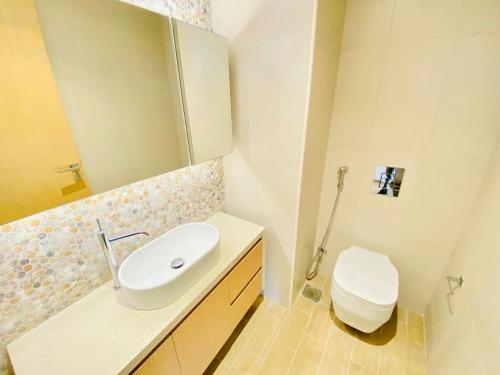 uma casa de banho com um lavatório branco e um WC. em Furnished & Serviced Studio em Abu Dhabi