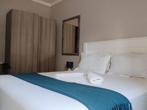 a bedroom with a white bed with a blue blanket on it at Chobe Blue Guest Inn in Kasane