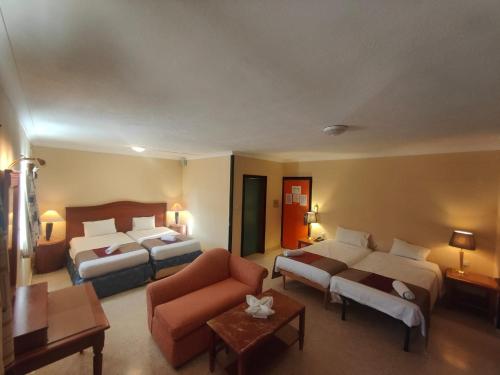 una camera d'albergo con due letti e un divano di The St. George’s Park Hotel a San Giuliano