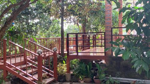 a wooden bridge in a garden with trees at Gibbon Singing Home Stay in Quan Tom