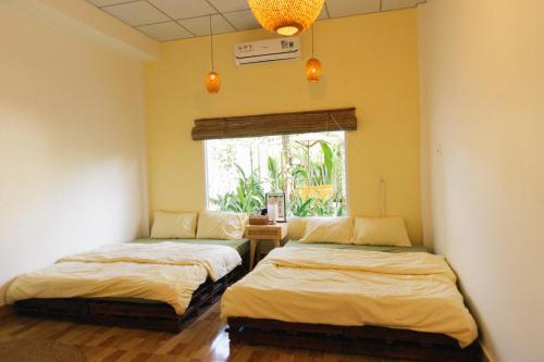 two beds in a room with a window at Entire First Floor - Nguyên Tầng Trệt- Nhà Mơ Homestay Bến Tre in Ben Tre