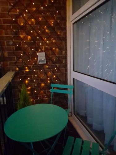 a green table and a chair in front of a window at Cosy Apartment with Balcony and Breakfast in Bishop Auckland