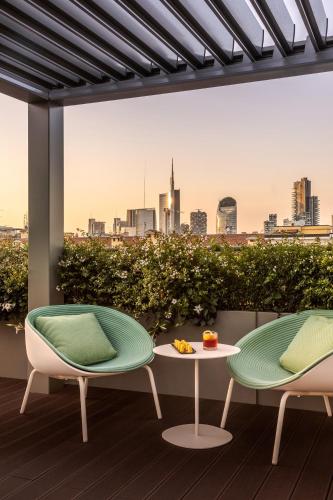 two chairs and a table on a balcony with a city at Casa Baglioni Milan - The Leading Hotels of the World in Milan