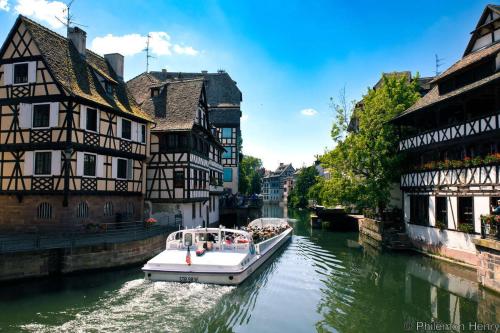 a boat on a river in a city with buildings at Cosy apartment on Strasbourg Tramway line and Canal - Appartement confortable sur ligne tram Strasbourg et Canal in Bischheim