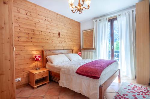 une chambre avec un lit et un mur en bois dans l'établissement CHAMOIS D'OR 1, à Morzine