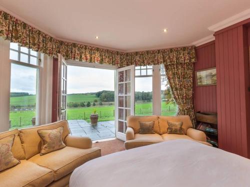 a bedroom with a bed and a large window at Country Lodge within Castle Ruins and own Loch 20 mins to St Andrews in Ceres