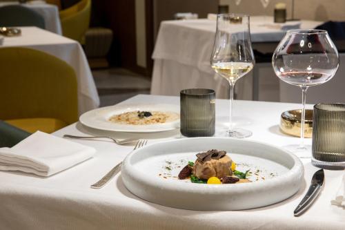 a white plate of food on a table with wine glasses at Casa Baglioni Milan - The Leading Hotels of the World in Milan