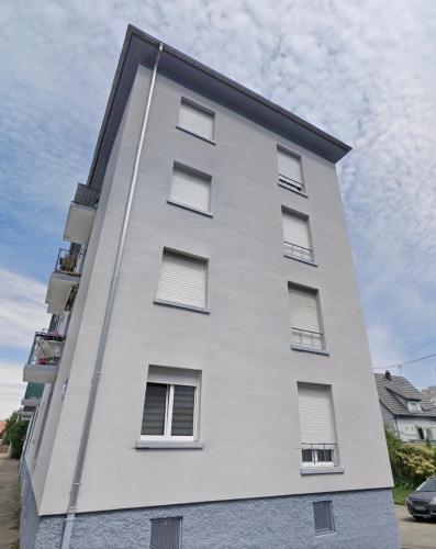a white building with windows on the side of it at Cosy apartment on Strasbourg Tramway line and Canal - Appartement confortable sur ligne tram Strasbourg et Canal in Bischheim