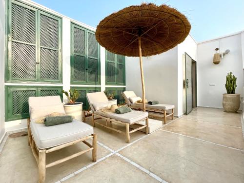 - une terrasse avec 2 chaises et un parasol dans l'établissement RIAD ILYM - Riad privatif Marrakech Medina, à Marrakech