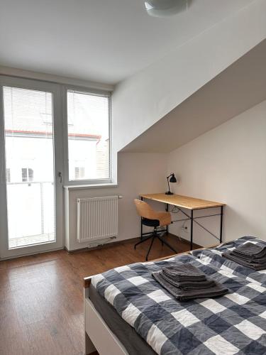 a bedroom with a bed and a desk and windows at Apartmán AB kryté parkování zdarma in České Budějovice