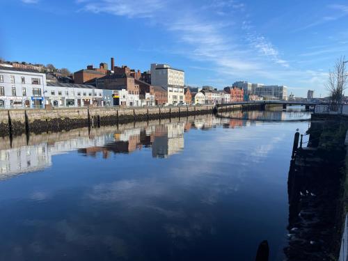 a river in a city with buildings and a bridge at Leitrim Property Cork in Cork