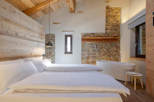 a bedroom with two beds and a stone wall at L’Ozio Creativo in Castelnuovo Nigra