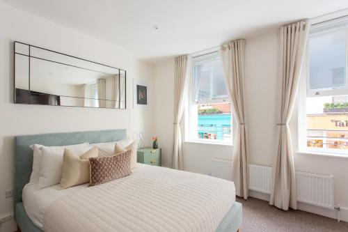 een slaapkamer met een bed met een spiegel en ramen bij 2 Bedroom Apartments in Covent Garden in Londen