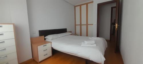 a small bedroom with a white bed and a dresser at Apartamento Guarnizo in Guarnizo