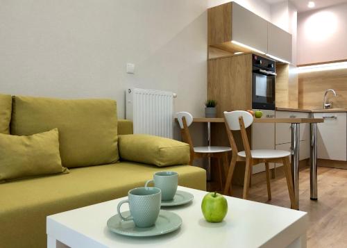 ein Wohnzimmer mit einem gelben Sofa und einer Küche in der Unterkunft Opera Park 23 by RENT4YOU in Olsztyn