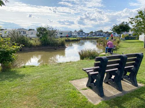 斯凱格內斯的住宿－Holidays with TLC at Cherry Lea Park，坐在河边公园长凳上的男人