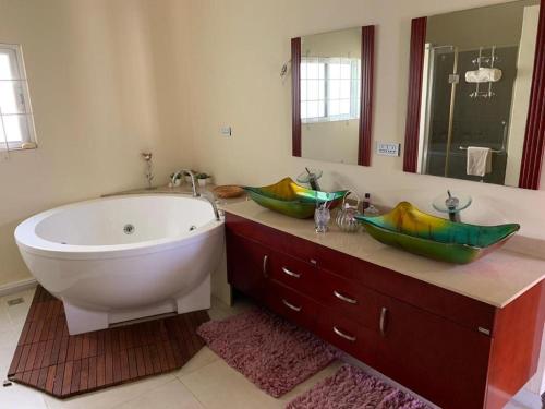 La salle de bains est pourvue d'une baignoire et d'un lavabo avec deux bols. dans l'établissement Inak villa, à Grand Baie