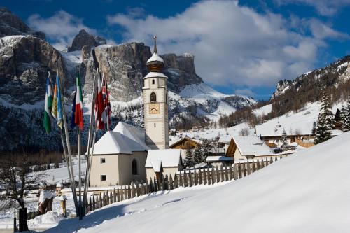 a building with a clock tower in the snow at Pensione Haus Erica in Colfosco