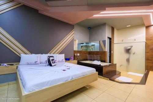 a bedroom with a large bed and a desk at Motel Deslize Ribeirão Preto in Ribeirão Preto