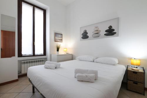 una camera da letto bianca con un grande letto bianco con asciugamani sopra di PrimoPiano - Scalvini a Milano