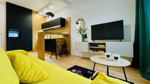 een woonkamer met een gele bank en een tv bij Opera Park 128 by RENT4YOU in Olsztyn