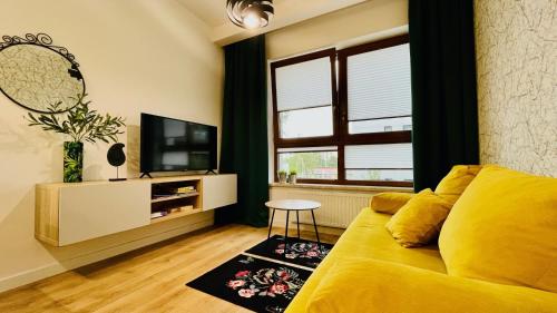 een woonkamer met een gele bank en een televisie bij Opera Park 128 by RENT4YOU in Olsztyn