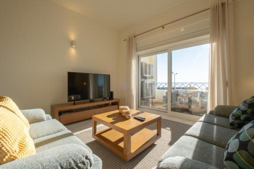 uma sala de estar com um sofá, uma televisão e uma mesa em Fábrica da Ribeira 54 by Destination Algarve em Lagos