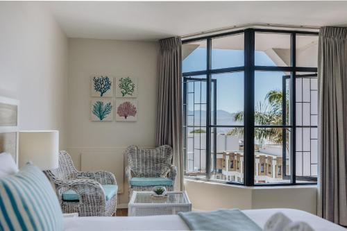 a bedroom with a bed and a large window at Bayview Hotel in Plettenberg Bay