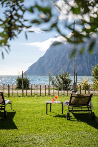 a park with two chairs and a table with flowers on it at Hotel Baia Azzurra - Lake Front in Nago-Torbole