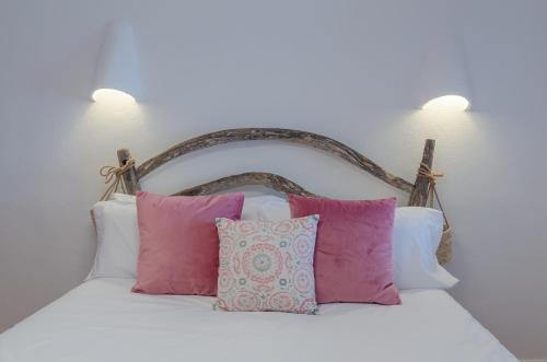 een bed met roze en witte kussens erop bij La maison dans la calanque 1 mn à pied de la plage d'ALCAUFAR 