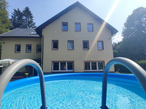 uma casa com piscina em frente a uma casa em Haus Wiesenbaude em Bärenstein