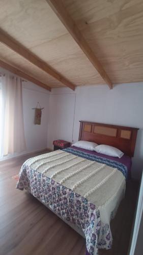 a bed in a bedroom with a wooden ceiling at Cerro Nevado in Puerto Tranquilo