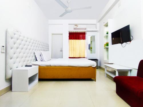 a bedroom with a large bed and a red couch at White Rose Suites Ltd in Dhaka