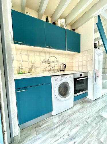 un lave-linge dans une cuisine avec des armoires bleues dans l'établissement Jolie petite maison à 500m de la plage d'Erdeven, à Erdeven