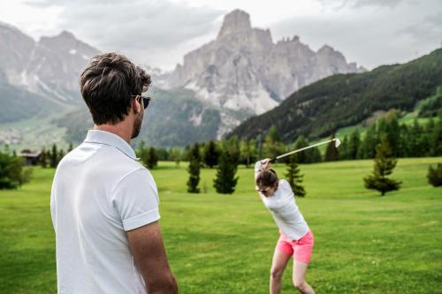 a man and a little girl swinging a baseball bat at Pensione Haus Erica in Colfosco