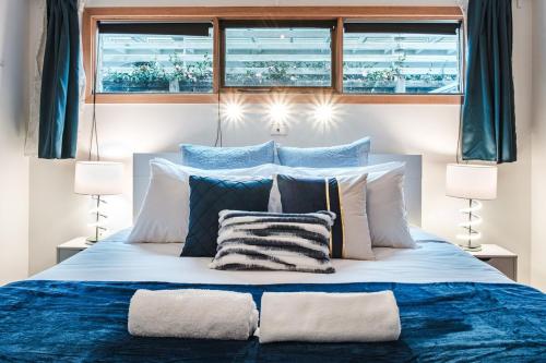 uma cama com almofadas azuis e brancas e duas janelas em Lakefront 4 Br House At Patterson Lake Kayakbbq em Patterson Lakes