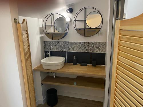a bathroom with a sink and two mirrors on the wall at La Bellours Chambre D'Hôtes in Cahors