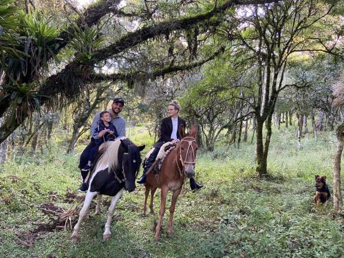 um grupo de pessoas montadas num cavalo com um cão em Chalés Recanto do Vale - GRALHA AZUL em Bom Jardim da Serra