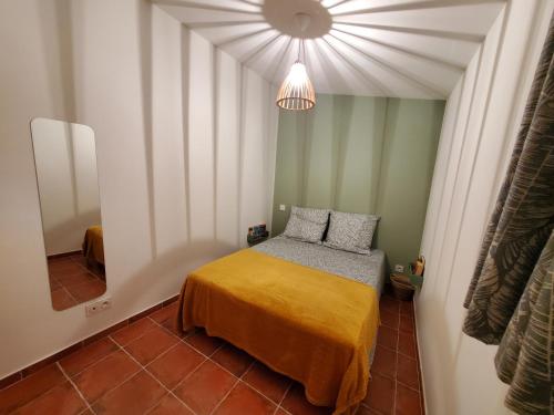 Dormitorio pequeño con cama con manta amarilla en Le Bleu Mimosa, en Narbona