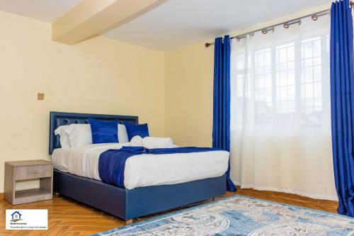 a bedroom with a bed with blue curtains and a window at Taliah Homestays in Nanyuki