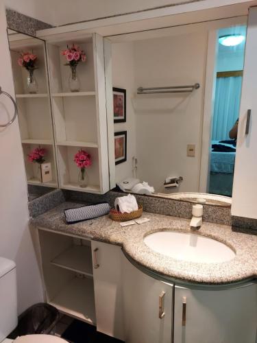 een badkamer met een wastafel en een spiegel bij Adriana Flats - Sem vista mar e sem varanda in Fortaleza