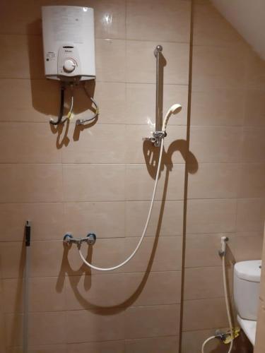 a shower in a bathroom with a hose on the wall at Orange Villa in Berastagi